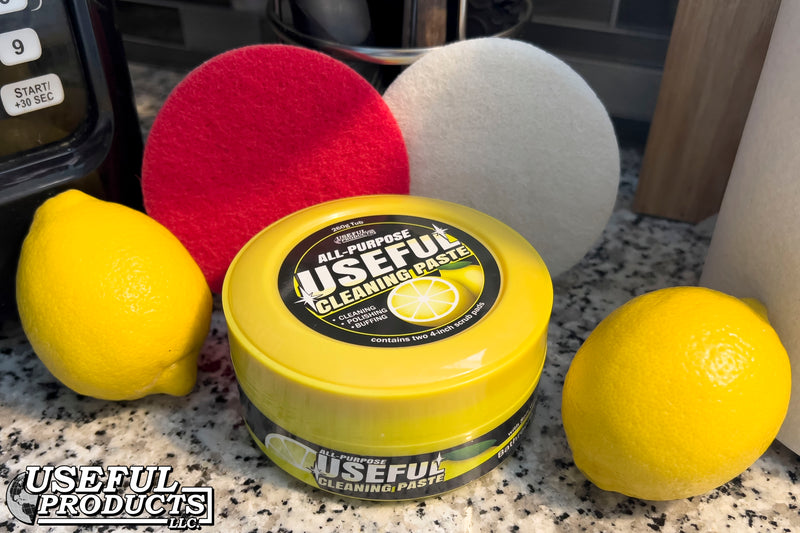 All-purpose Useful Cleaning Paste with Soft White and Stiff Red scrub pads on a kitchen countertop near two lemons.