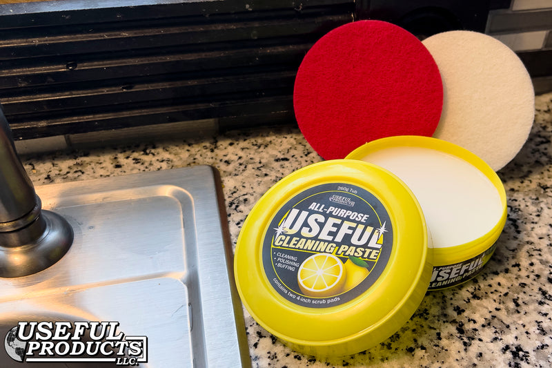 An open container of All-purpose Useful Cleaning Paste on a kitchen countertop infront of Soft White and Stiff Red scrub pads.