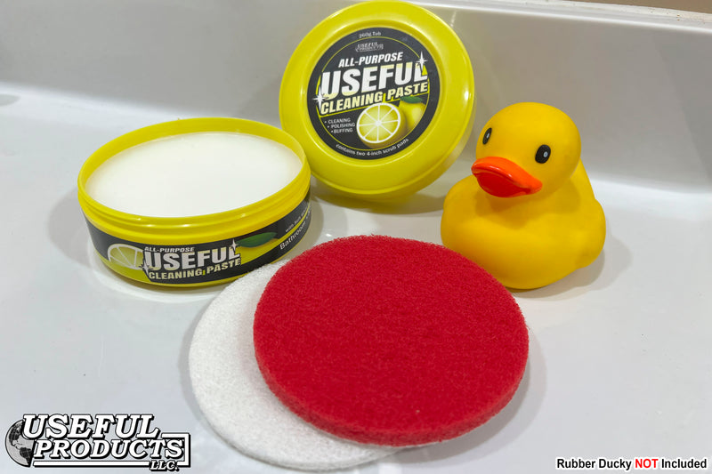 An open container of All-purpose Useful Cleaning Paste on a bathroom counter with Soft White and Stiff Red scrub pads and a rubber ducky named Kendrick.