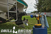 Drillbrush 2 inch Short Medium Blue Marine & Pool Brush in a cordless drill on a bucket next to a spray bottle and rag in front of a boat on a trailer in a backyard.
