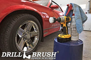 Drillbrush 2 inch Short Soft White Home & Auto Brush in a cordless drill on a bucket next to a spray bottle and shop rag in front of the rims of a red sports car.