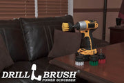 The Drillbrush Soft White, Medium Yellow, Medium Green, and Stiff Red 2 inch Short 4-piece Variety Brush Kit on a wooden desk in front of a leather sofa.