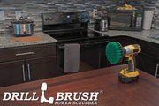 Drillbrush 5 inch Medium Green Kitchen Brush on a table in front of a kitchen counter, stove, microwave, and other appliances.