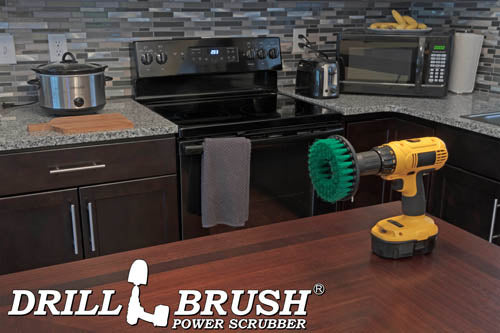 Drillbrush 5 inch Hex Medium Green Kitchen Brush on a table in front of a kitchen counter, stove, microwave, and other appliances.