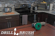 Drillbrush 5 inch Threaded Medium Green Kitchen Brush on a table in front of a kitchen counter, stove, microwave, and other appliances.