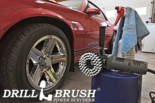 Drillbrush 5 inch Threaded Soft White Home & Auto Brush in a variable speed polisher on a bucket next to a spray bottle and shop rag in front of the rims of a red sports car.