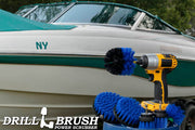 The Drillbrush 542OMS-2L Medium Blue Marine & Pool Brush Kit in a cordless drill sitting on a bucket in front of a boat on a trailer.