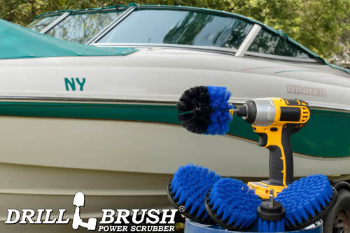 The Drillbrush 5542O Medium Blue Marine & Pool Brush Kit in a cordless drill sitting on a bucket in front of a boat on a trailer.