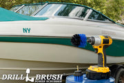The Drillbrush 2M Medium Blue Marine & Pool Brush Kit in a cordless drill sitting on a bucket in front of a boat on a trailer.