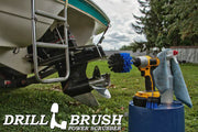 The Drillbrush 2O Medium Blue Marine & Pool Brush Kit in a cordless drill sitting on a bucket next to a spray bottle and rag in front of a boat on a trailer in a backyard.