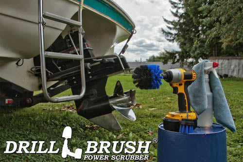 The Drillbrush 2O Medium Blue Marine & Pool Brush Kit in a cordless drill sitting on a bucket next to a spray bottle and rag in front of a boat on a trailer in a backyard.
