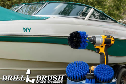 The Drillbrush 542O Medium Blue Marine & Pool Brush Kit in a cordless drill sitting on a bucket in front of a boat on a trailer.
