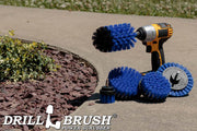 The Drillbrush E542J Medium Blue Marine & Pool Brush Kit in a cordless drill sitting on a sidewalk next to a rock garden.