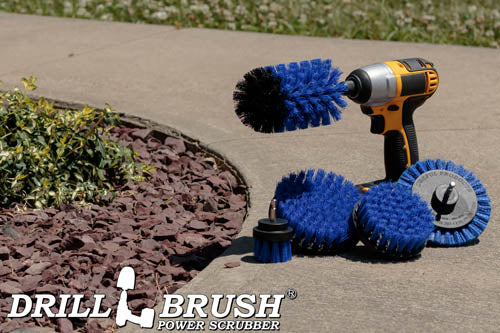 The Drillbrush E542J Medium Blue Marine & Pool Brush Kit in a cordless drill sitting on a sidewalk next to a rock garden.
