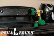 The Drillbrush 4OS-2L Medium Green Kitchen Brush Kit in a cordless drill sitting on a stovetop in front of a coffeemaker.