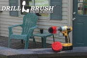 The Drillbrush 4M Red Stiff Outdoor & Patio Brush Kit in a cordless drill sitting on a deck railing in front of vinyl furniture.