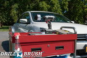 The Drillbrush 2M Soft White Home & Auto Brush Kit in a cordless drill sitting on a tool cart in front of a white sedan.