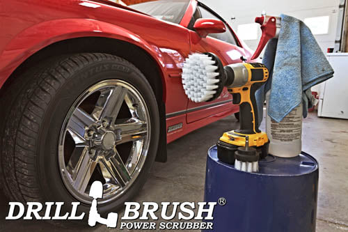 The Drillbrush 42 Soft White Home & Auto Brush Kit in a cordless drill sitting on a bucket next to a spray bottle and a rag in front of a red sports car.