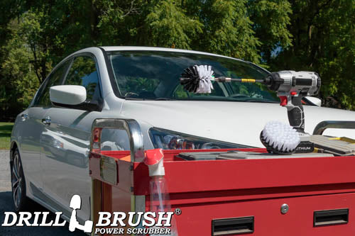 The Drillbrush 4M-5X Medium Green Kitchen Brush Kit in a cordless drill sitting on a tool cart in front of a white sedan.