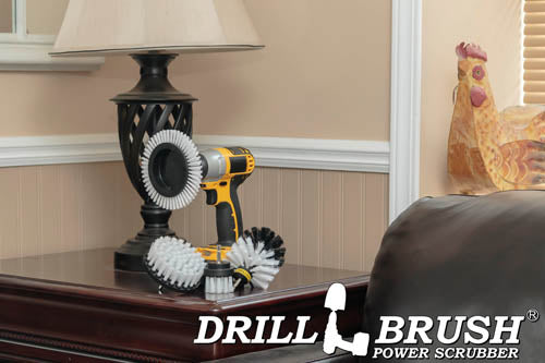 The Drillbrush E42O Soft White Home & Auto Brush Kit in a cordless drill sitting on a side table in front of a lamp next to a leather sofa.