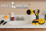 The Drillbrush 42OS-2L Medium Yellow Bathroom Brush Kit in a cordless drill sitting on a bathroom counter next to a sink and toiletries.