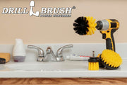 The Drillbrush 4OS-2L Medium Yellow Bathroom Brush Kit in a cordless drill sitting on a bathroom counter next to a sink and toiletries.