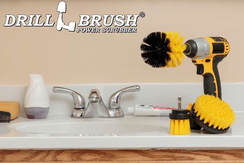 The Drillbrush 4OS-2L Medium Yellow Bathroom Brush Kit in a cordless drill sitting on a bathroom counter next to a sink and toiletries.