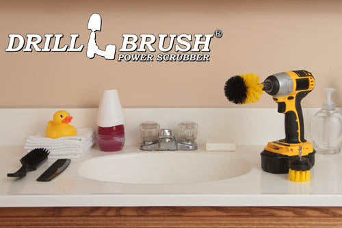 The Drillbrush 2M Medium Yellow Bathroom Brush Kit in a cordless drill sitting on a bathroom counter next to a sink and toiletries.