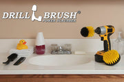 The Drillbrush 4M Medium Yellow Bathroom Brush Kit in a cordless drill sitting on a bathroom counter next to a sink and toiletries.