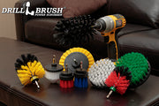 The Drillbrush 9-piece kit featuring Soft White Cone and 4 inch brushes, Medium Yellow Edge and Original brushes, Medium Green 5 inch brush, Medium Blue 2 inch Long brush, Stiff Red 2 inch Short and Mini Original brushes, and Ultra Stiff Jumbo Original brush on a living room coffee table.