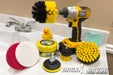 Drillbrush Medium Yellow 4 inch, 2 inch Short, and Original brushes with a Soft White and Stiff Red 4 inch scrub pad, a 3 inch pad backer, and All-Purpose Useful Cleaning Paste in front of a drill that is holding the Original brush. The kit and drill are resting on a bathroom sink counter near a rubber duck.