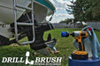 Drillbrush 2 inch Long Medium Blue Marine & Pool Brush in a cordless drill on a bucket next to a spray bottle and rag in front of a boat on a trailer in a backyard.