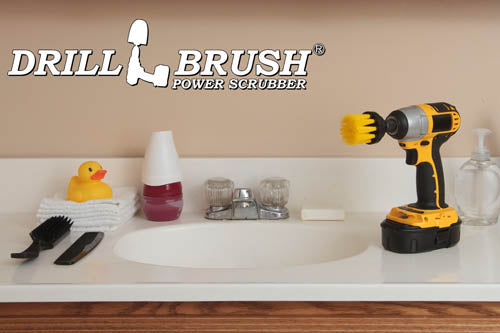 Drillbrush 2 inch Long Medium Yellow Bathroom Brush in a cordless drill on a bathroom counter in front of a sink and some toiletries.