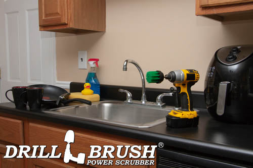 Drillbrush 2 inch Long Medium Green Kitchen Brush on a kitchen counter next to a sink in front of dishes and an air fryer.