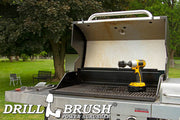 Drillbrush 2 inch Short Ultra Stiff Black Grill & Industrial Brush in a cordless drill on an open grill in front of a backyard.