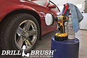 Drillbrush 4 inch Soft White Home & Auto Brush in a cordless drill on a bucket next to a spray bottle and shop rag in front of the rims of a red sports car.