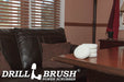 The Drillbrush Soft White 4 inch Scrubbing Pad Refill Kit in a stack on a wooden desk in front of a leather sofa in a personal office.