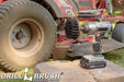Drillbrush 4 inch Ultra Stiff Black Grill & Industrial Brush in a cordless drill on stone bricks in front of a lawnmower.