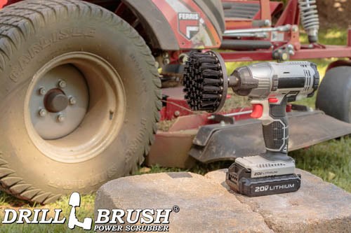 Drillbrush 4 inch Ultra Stiff Black Grill & Industrial Brush in a cordless drill on stone bricks in front of a lawnmower.