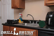 The Drillbrush Abrasive Green 5 inch Scrubbing Pad on a kitchen counter in front of a sink, dishes, and a coffeemaker.
