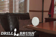 The Drillbrush Soft White 5 inch Scrubbing Pad on a wooden desk in front of a leather sofa in a personal office.