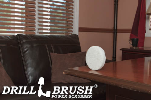 The Drillbrush Soft White 5 inch Scrubbing Pad on a wooden desk in front of a leather sofa in a personal office.