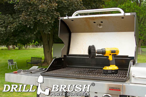 Drillbrush 5 inch Hex Ultra Stiff Black Grill & Industrial Brush in a cordless drill on an open grill in front of a backyard.