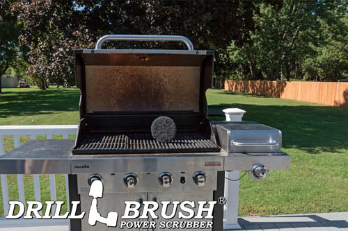 The Drillbrush Aggressive Black 6 inch Scrubbing Pad on an open grill on a deck in front of a backyard.