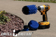 The Drillbrush 42J Medium Blue Marine & Pool Brush Kit in a cordless drill on a sidewalk next to a rock garden.