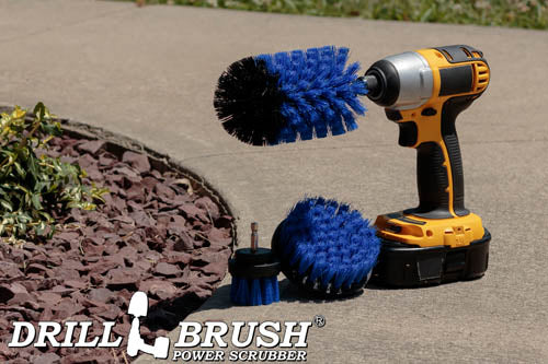The Drillbrush 42J Medium Blue Marine & Pool Brush Kit in a cordless drill on a sidewalk next to a rock garden.