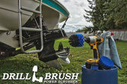 The Drillbrush 42O Medium Blue Marine & Pool Brush Kit in a cordless drill sitting on a bucket next to a spray bottle and rag in front of a boat on a trailer in a backyard.