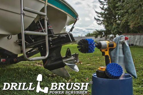 The Drillbrush 4O Medium Blue Marine & Pool Brush Kit in a cordless drill sitting on a bucket next to a spray bottle and rag in front of a boat on a trailer.