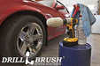 The Drillbrush Cotton Buffer in a cordless drill on a bucket next to a spray bottle and rag in front of a red sports car in a garage.