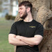 Model wearing the Drillbrush black polyester t-shirt in a public setting.